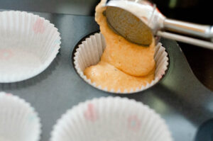 Pouring batter into lined muffin pan.