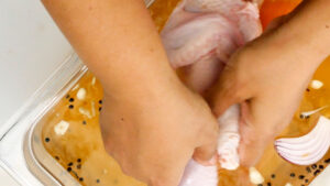 Placing chicken in marinade.